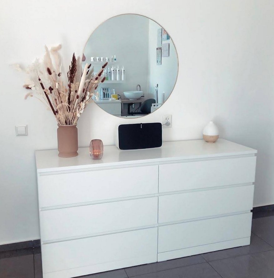 Witte ladekast met een ronde spiegel, gedroogde pampas en een diffuser